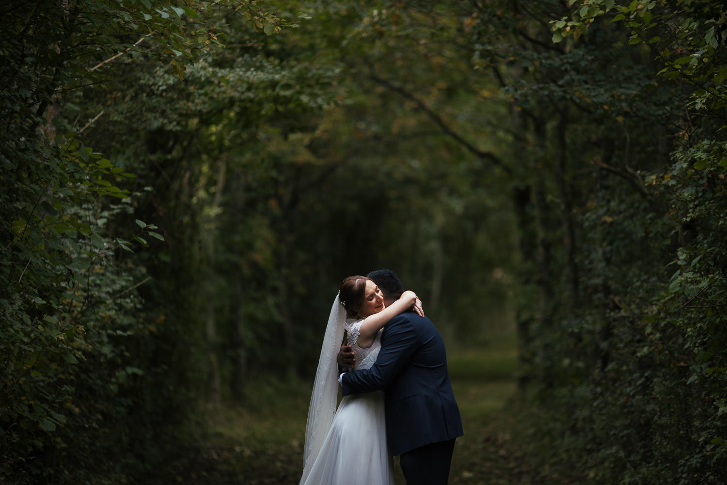 Bride and groom hugging in the grassy lane at Alpheton Hall Barns.