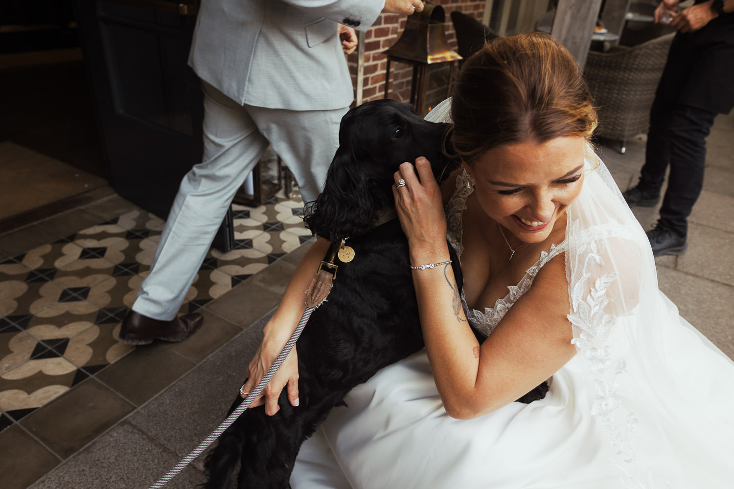 Bride crouched on floor hugging her dog. At The Lion House wedding venue in Chelmsford.