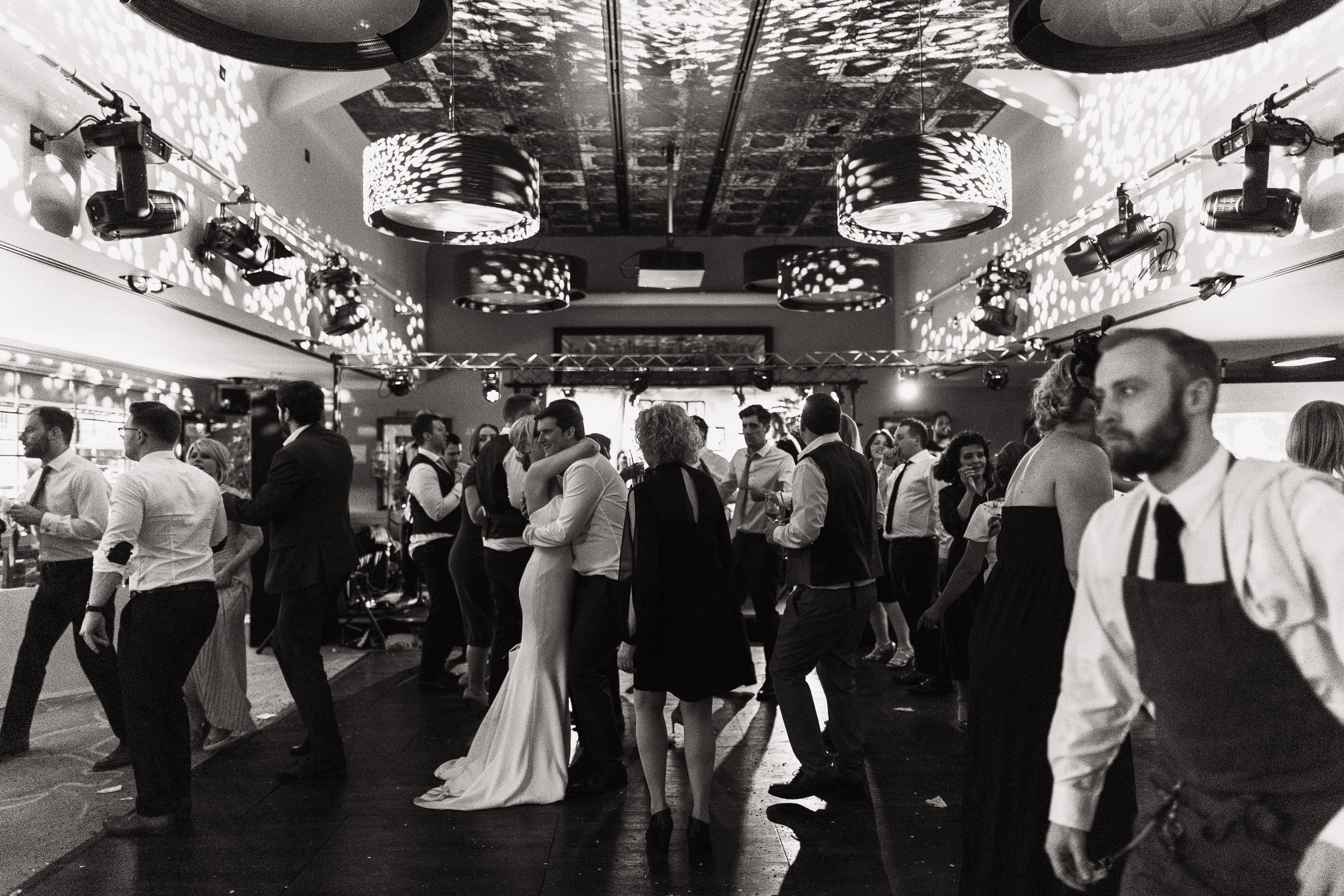 A busy dance floor at The Lion House, a popular Essex wedding venue. Newlyweds dance at the center while a waiter walks by. Located near Chelmsford and conveniently accessible from the A12.