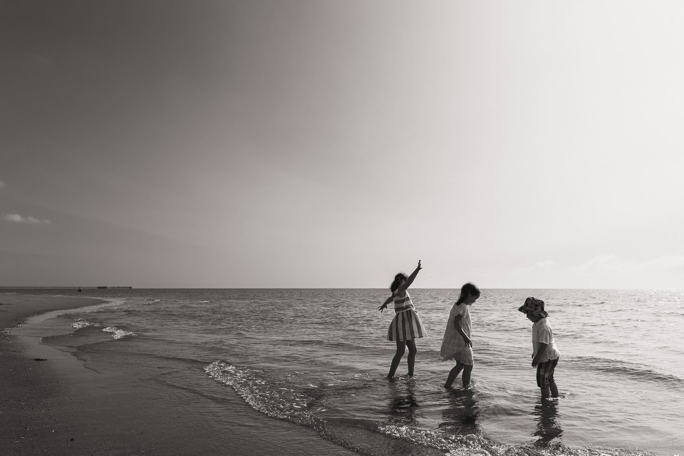 Three children playing on the beach in Frinton. A natural family photography shoot in Essex.