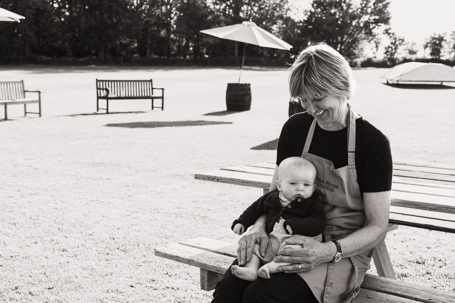 Bridget of Anna Shutes catering keeping a guest's baby occupied during wedding breakfast. Sat on a picnic table outside the marquee.