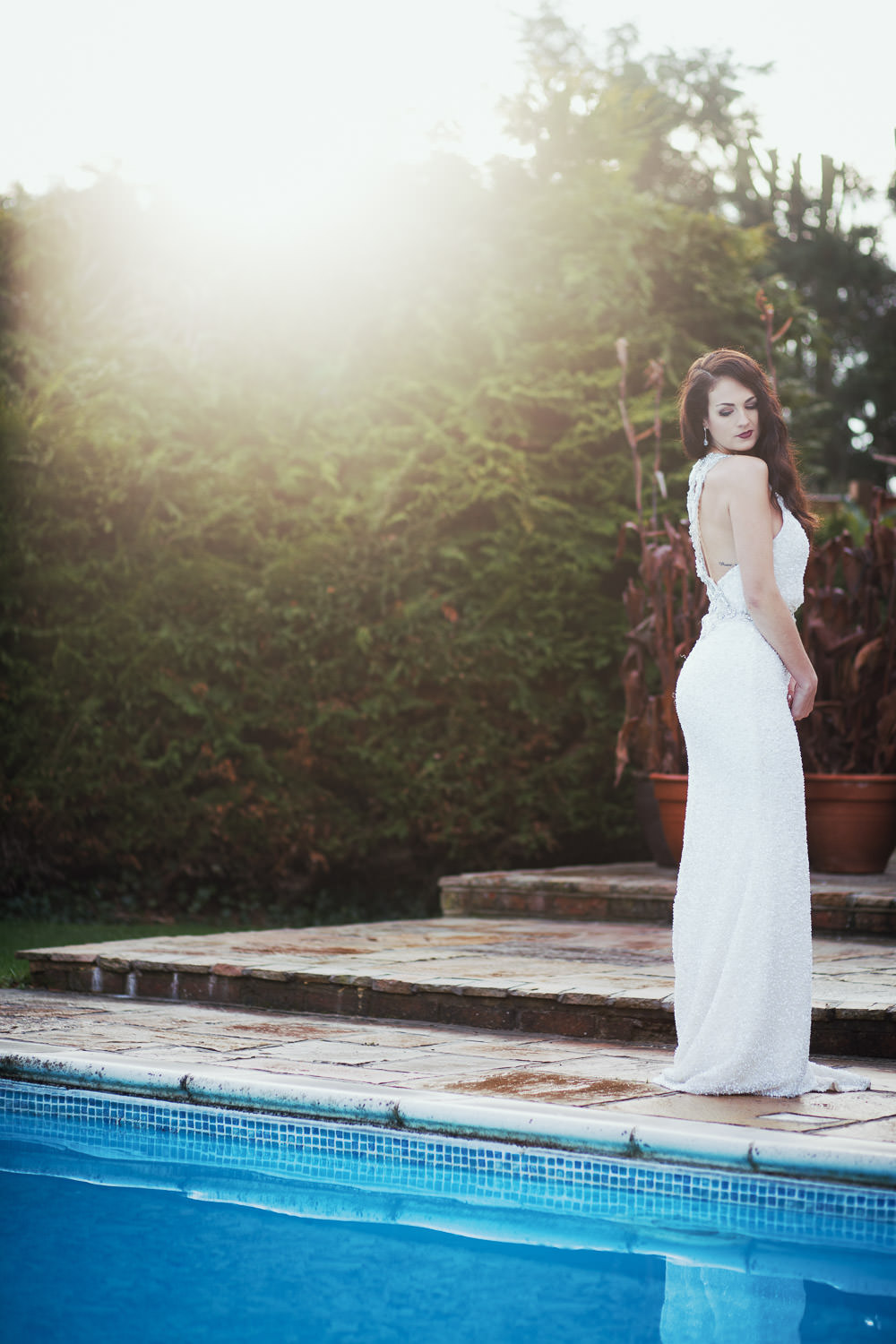 Amelia from Bellissima Weddings, a bridal shop in South Woodham Ferrers. She is wearing Badgley Mischka dress Adele. Standing by the pool at High House in Althorne.