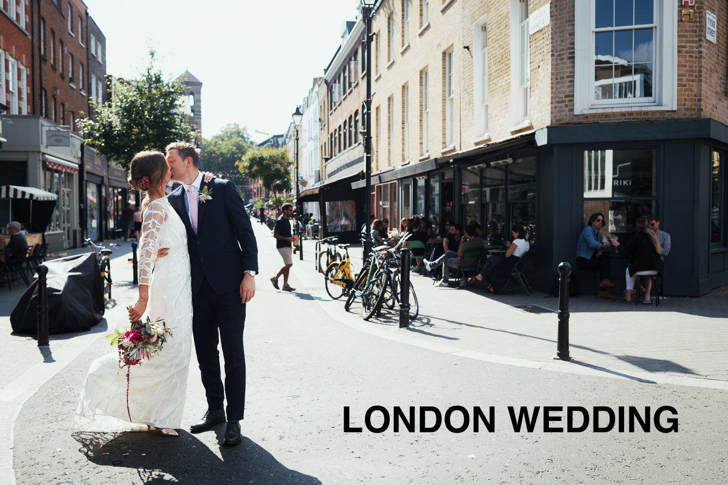 Newly married couple near Exmouth Market on the corning of Tysoe Street on their wedding day. Outside the Briki cafe.The bride is wearing the Willow Halfpenny dress.
