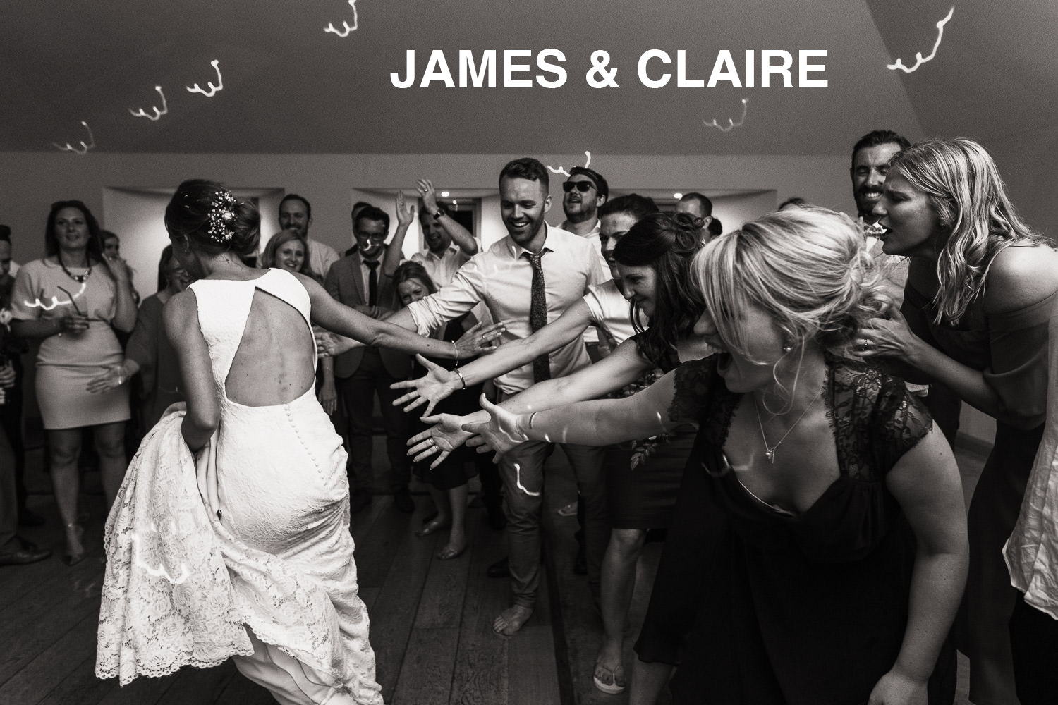 Wedding photography at Houchins wedding venue in Essex. A bride runs around the dance floor as the guests reach out their hands.