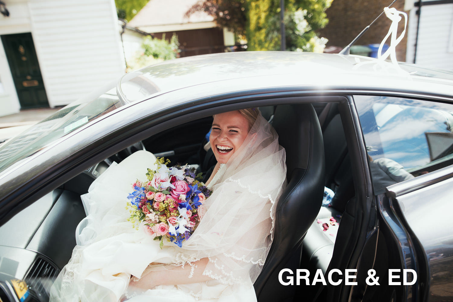 Bride getting in the car smiling after her wedding at St Giles & All Saints Church, Orsett. Holding a bouquet and wearing a veil.