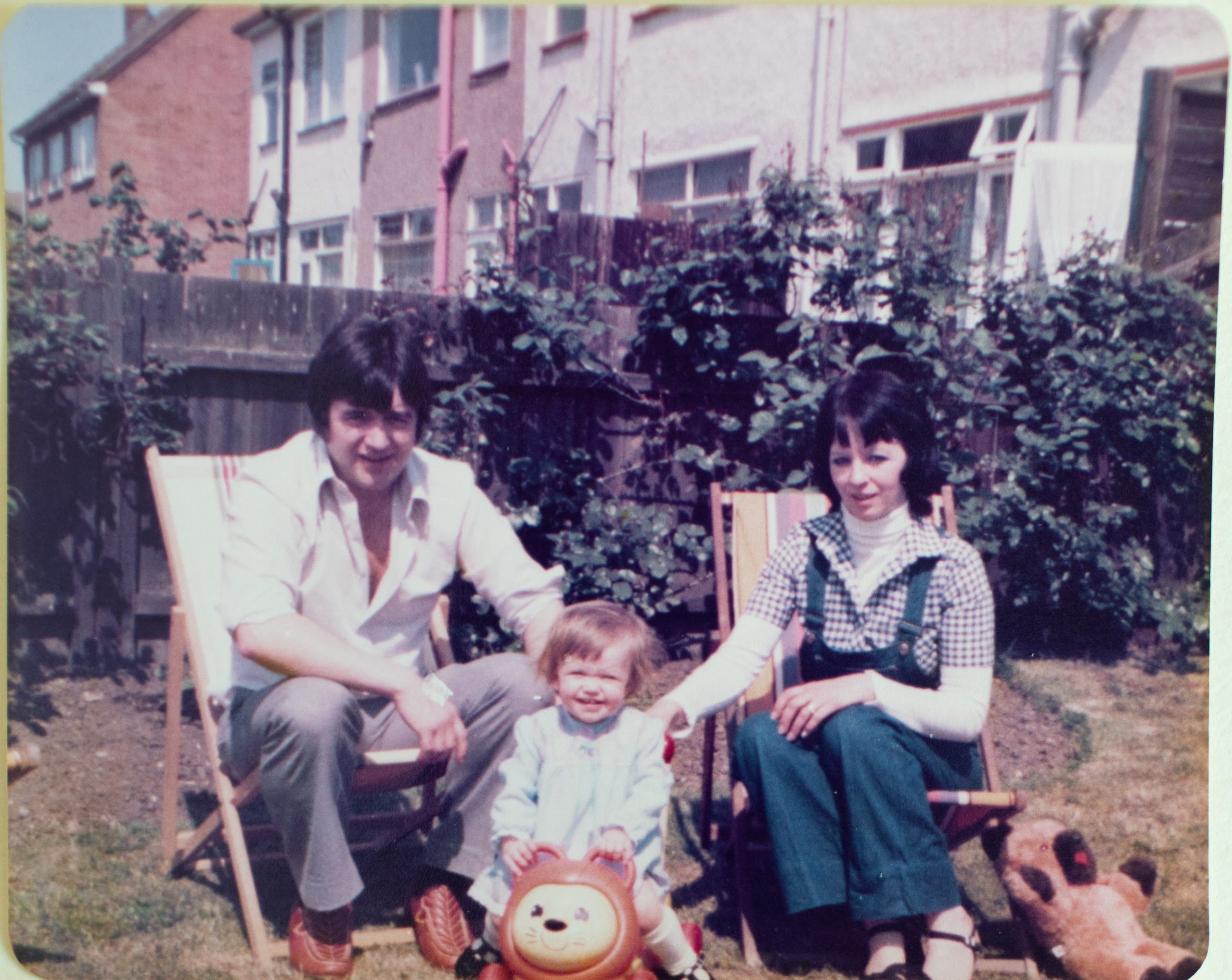 Toddler with parents in a garden in the early 1980s.