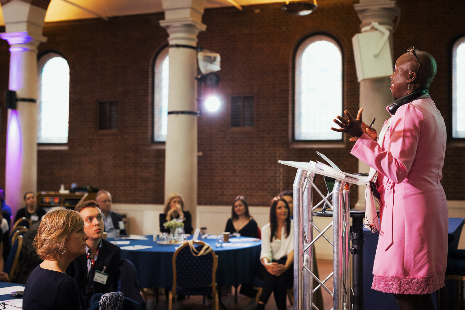 Woman wearing pink given at talk at a conference.