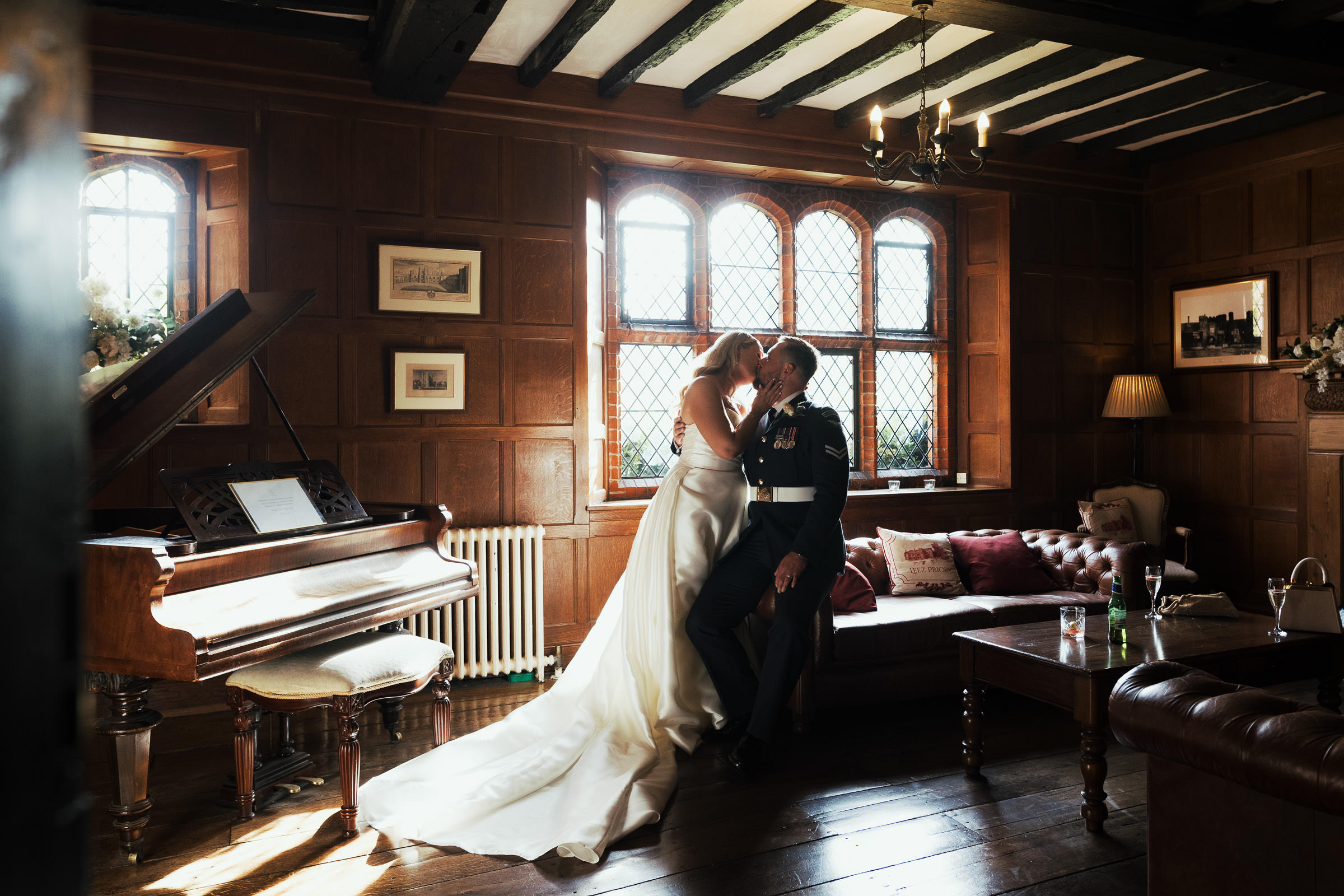 Leez Priory Wedding Photography: Bride and groom kissing in the Light Oak Room. Bride wearing Élysée Delancey ball gown from MiliMili bridal. Groom in his Royal Air Force Corporal Uniform.