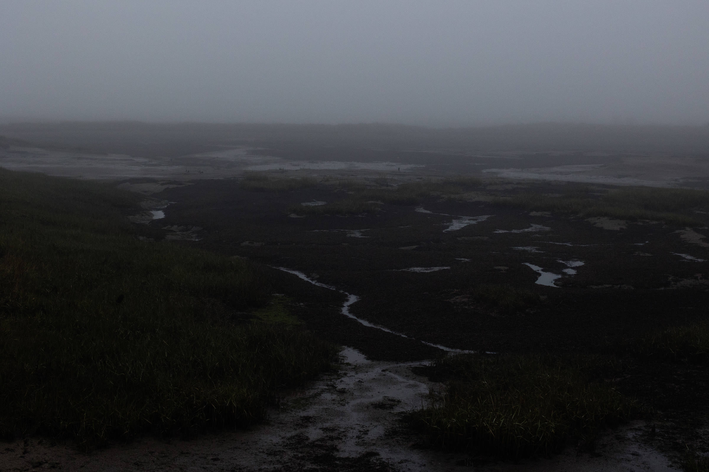 South Woodham Ferrers. A dark, foggy winter scene at low tide in Clements Green Creek, located in Marsh Farm Country Park, a Site of Special Scientific Interest (SSSI).