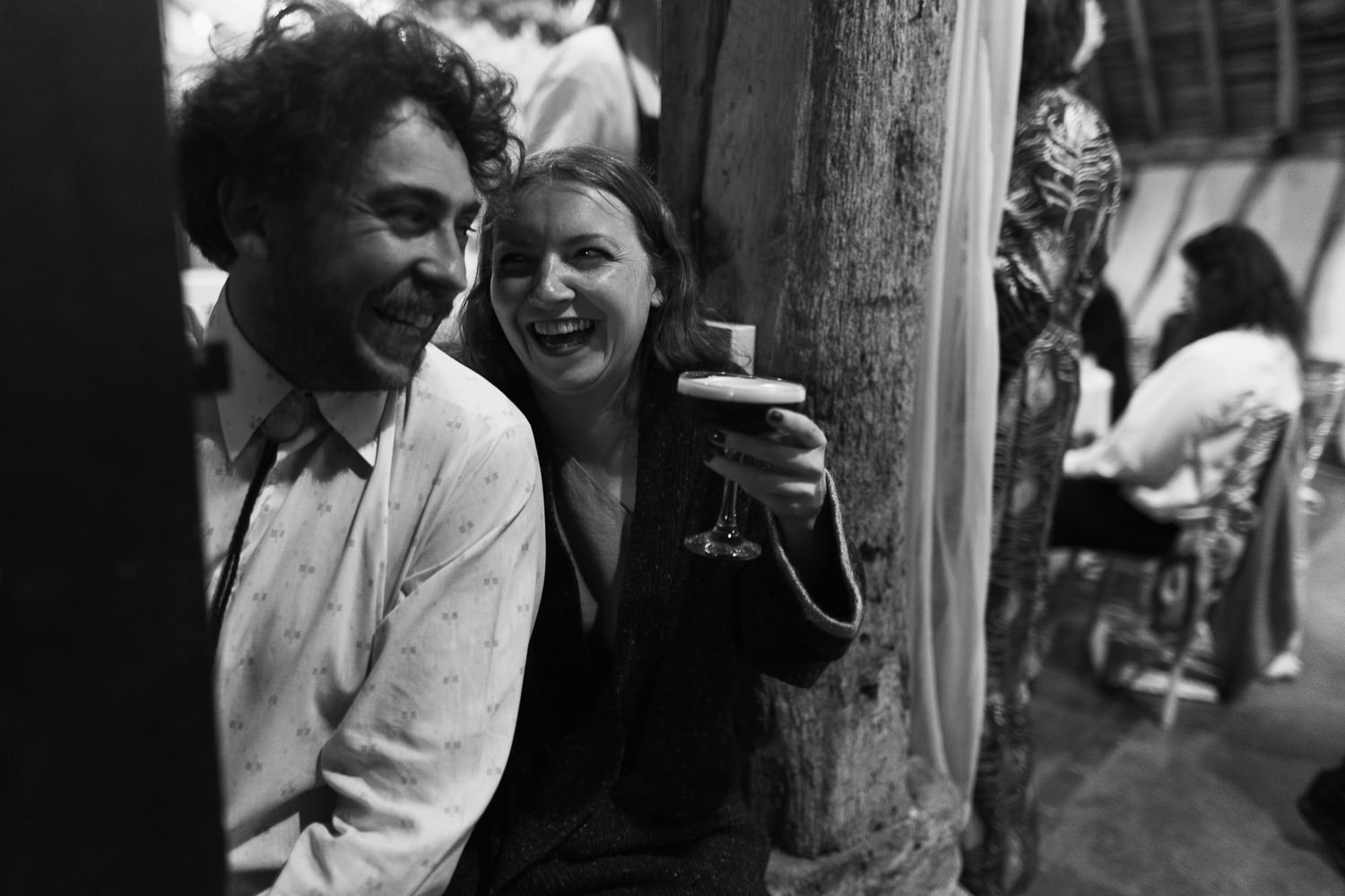 Two people enjoying a cocktail at a wedding a Alpheton Hall Barns. Candid wedding photography.