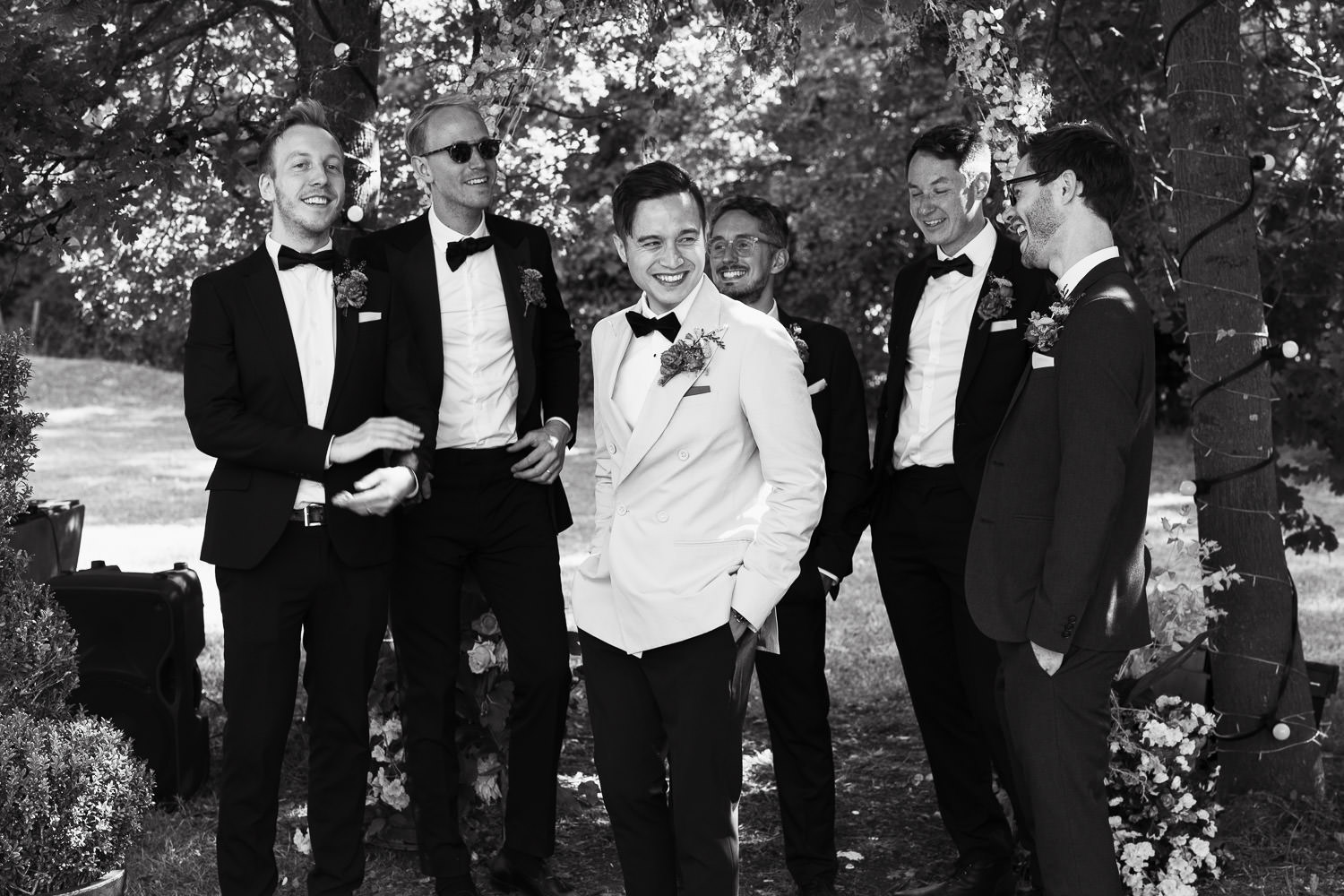 A groom and groomsmen in black tie at a summer festival themed garden wedding.