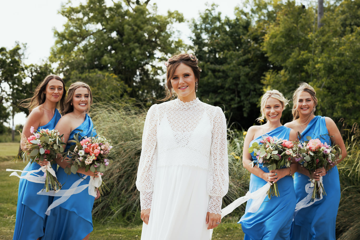 Bride in long sleeved outfit, bridesmaids wearing blue.