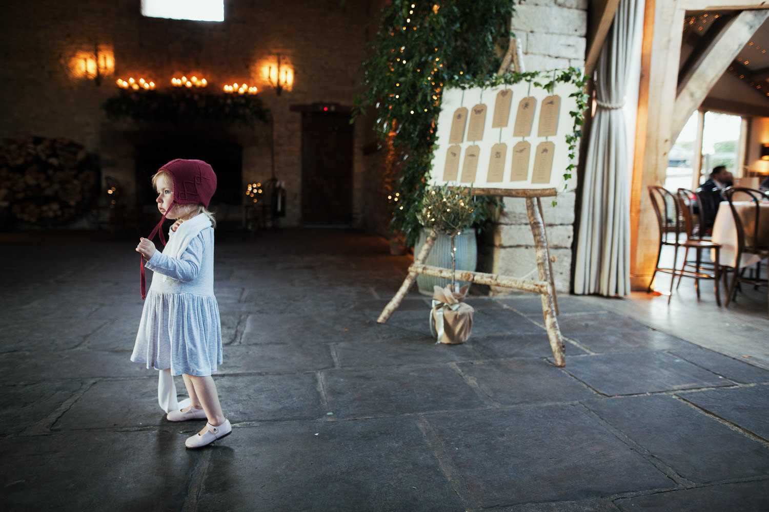 A small girl with a red knitted hat at Cripps Barn wedding venue.