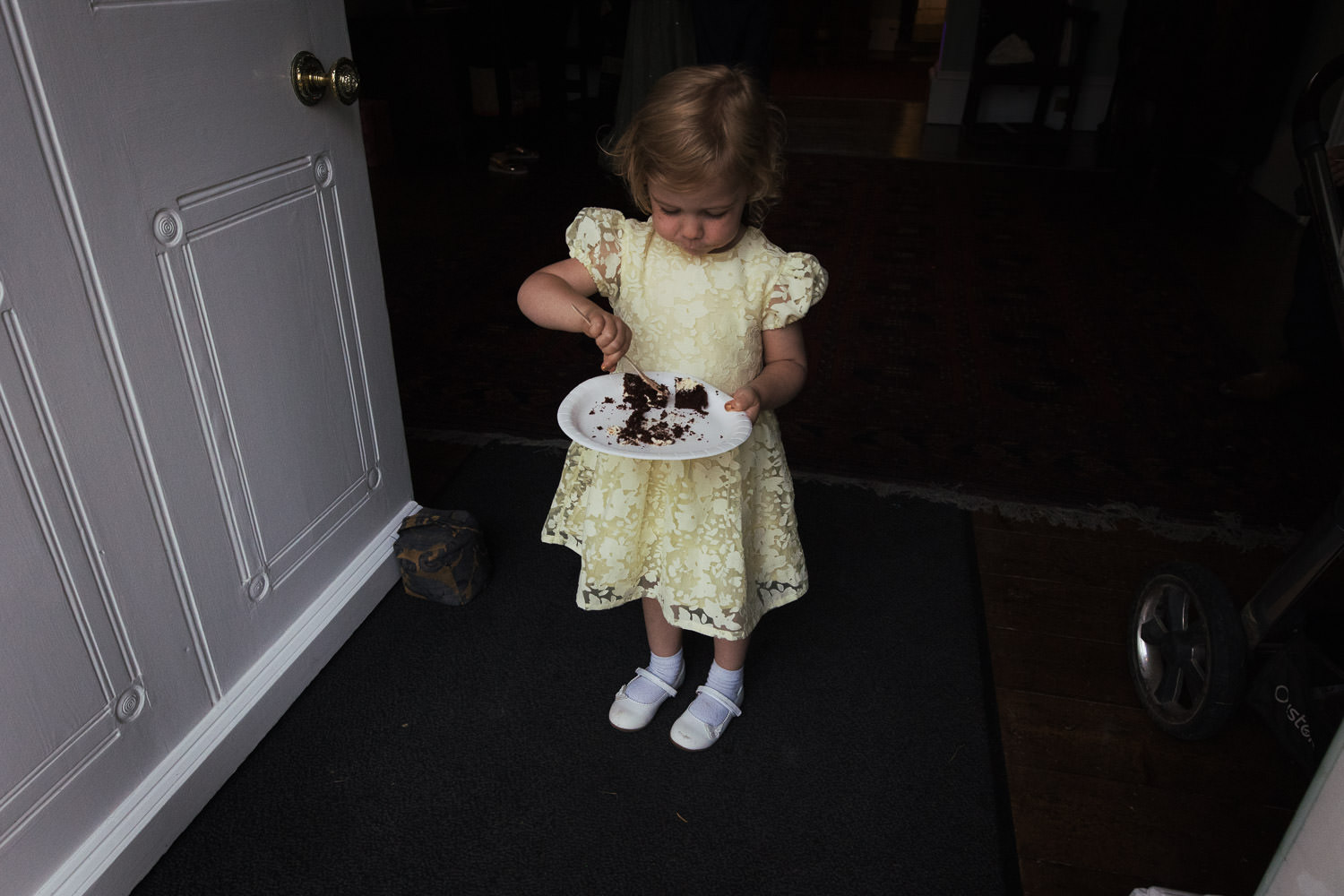 Girl in a yellow dress eating cake from a paper plate in the doorway of Homme House.