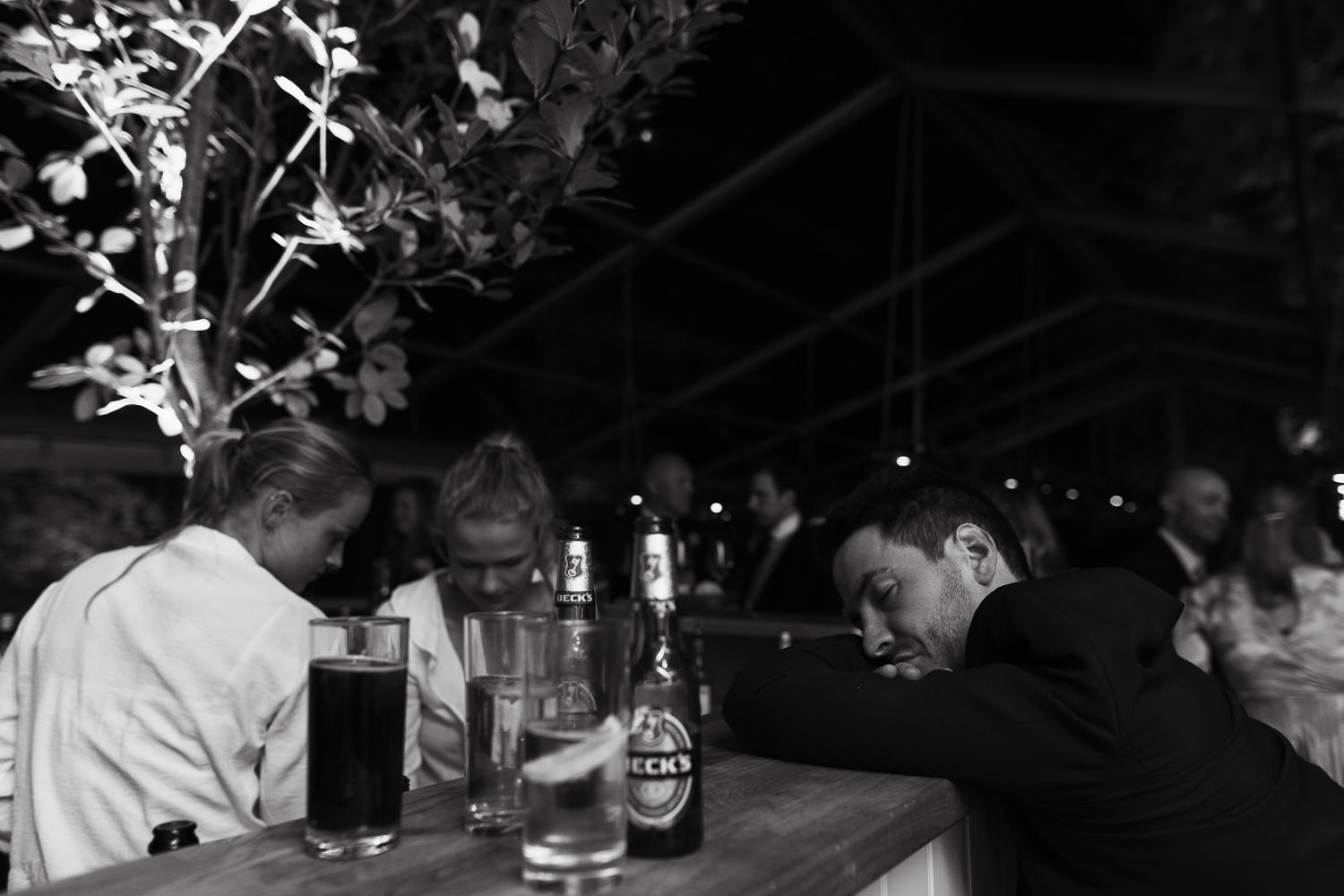 Man resting on a bar at a wedding reception.