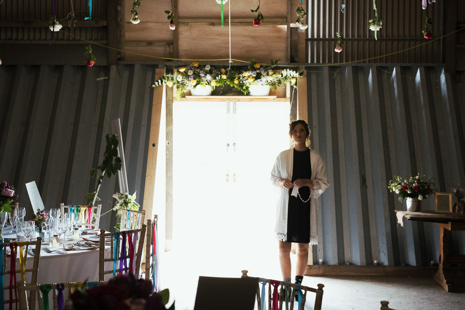 A woman in odd socks and white dressing gown in the doorway of a barn dressed for a wedding.