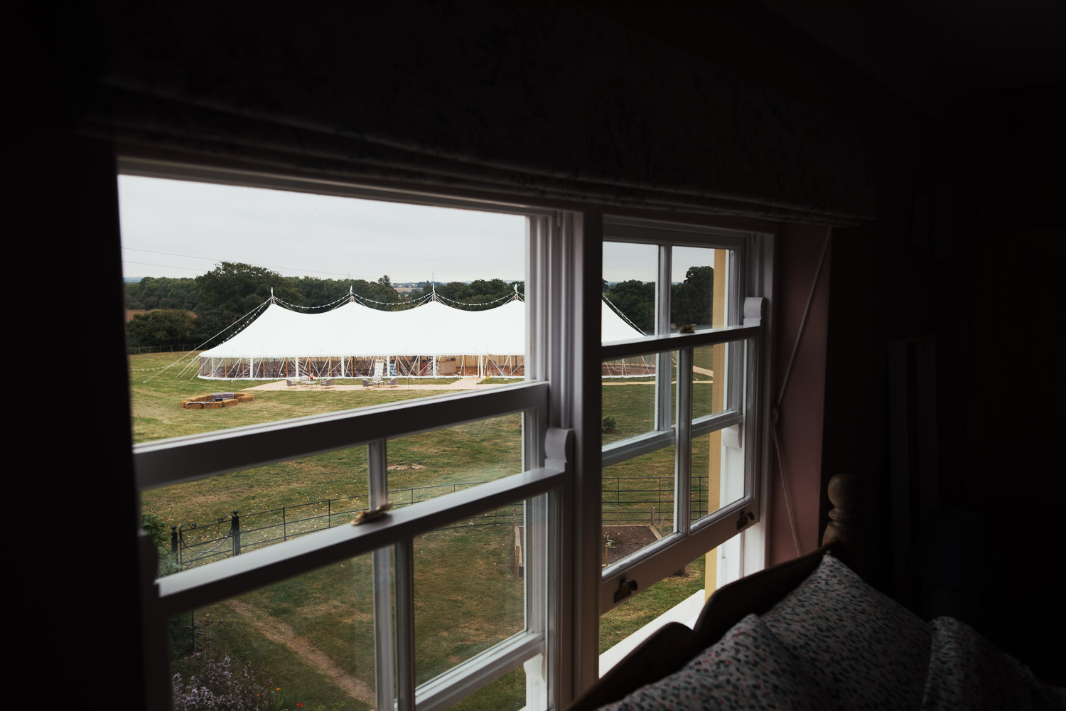 View of a Sail & Peg marquee in the garden seen through the window of a bedroom at Wellinditch Farmhouse. This home-hosted wedding near South Woodham Ferrers was beautifully captured by local documentary photographer Tracy.