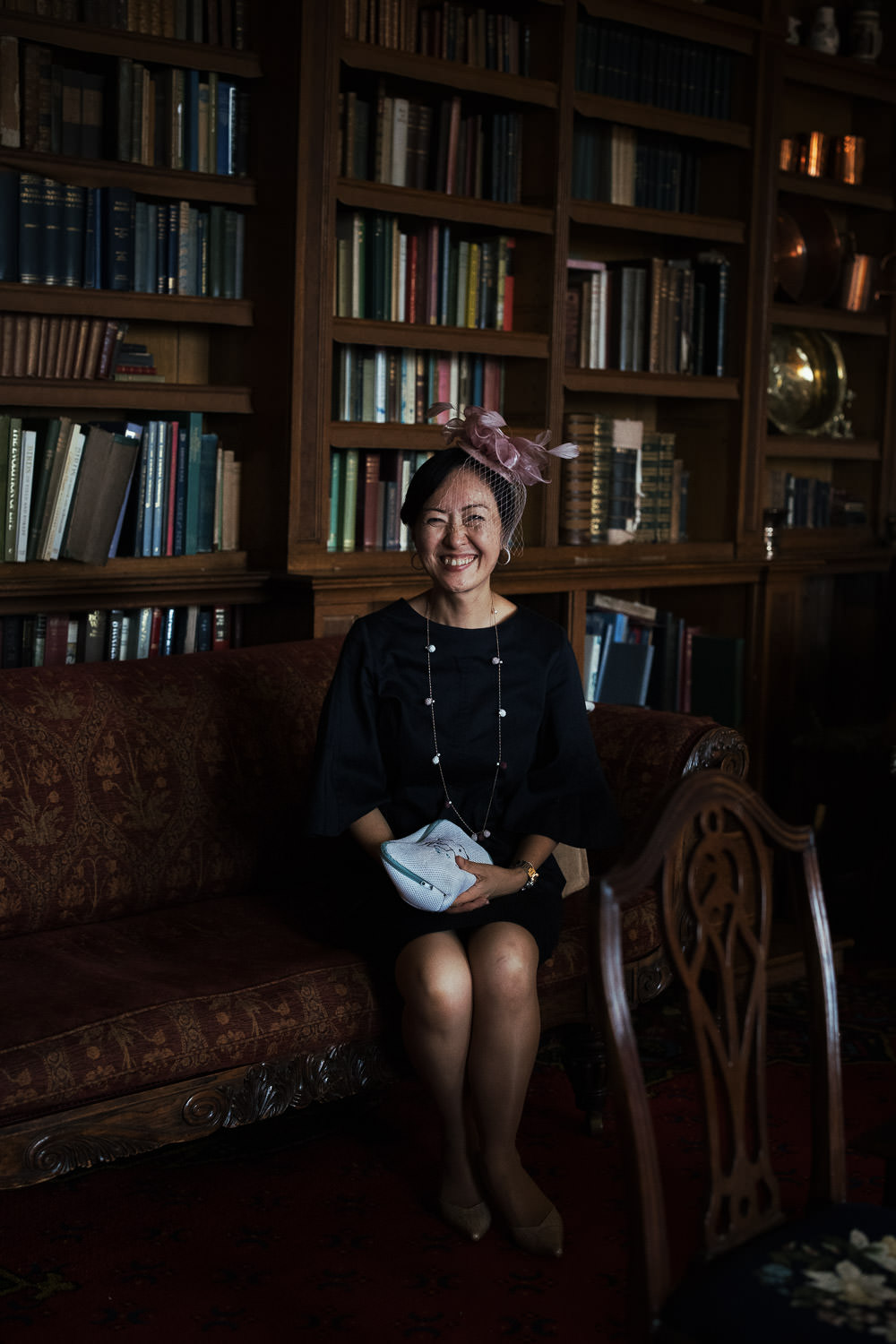 Unposed portrait of a wedding guest sat on a sofa in the library of Homme House wedding venue.