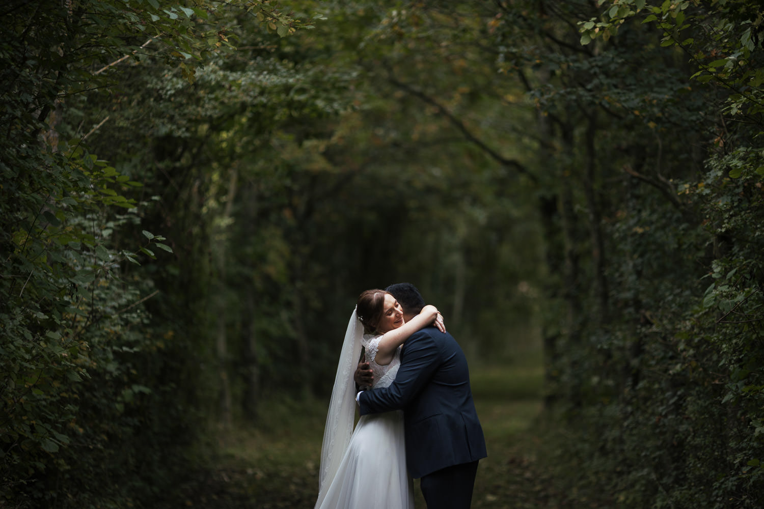 Bride and groom hugging in the grassy lane at Alpheton Hall Barns.