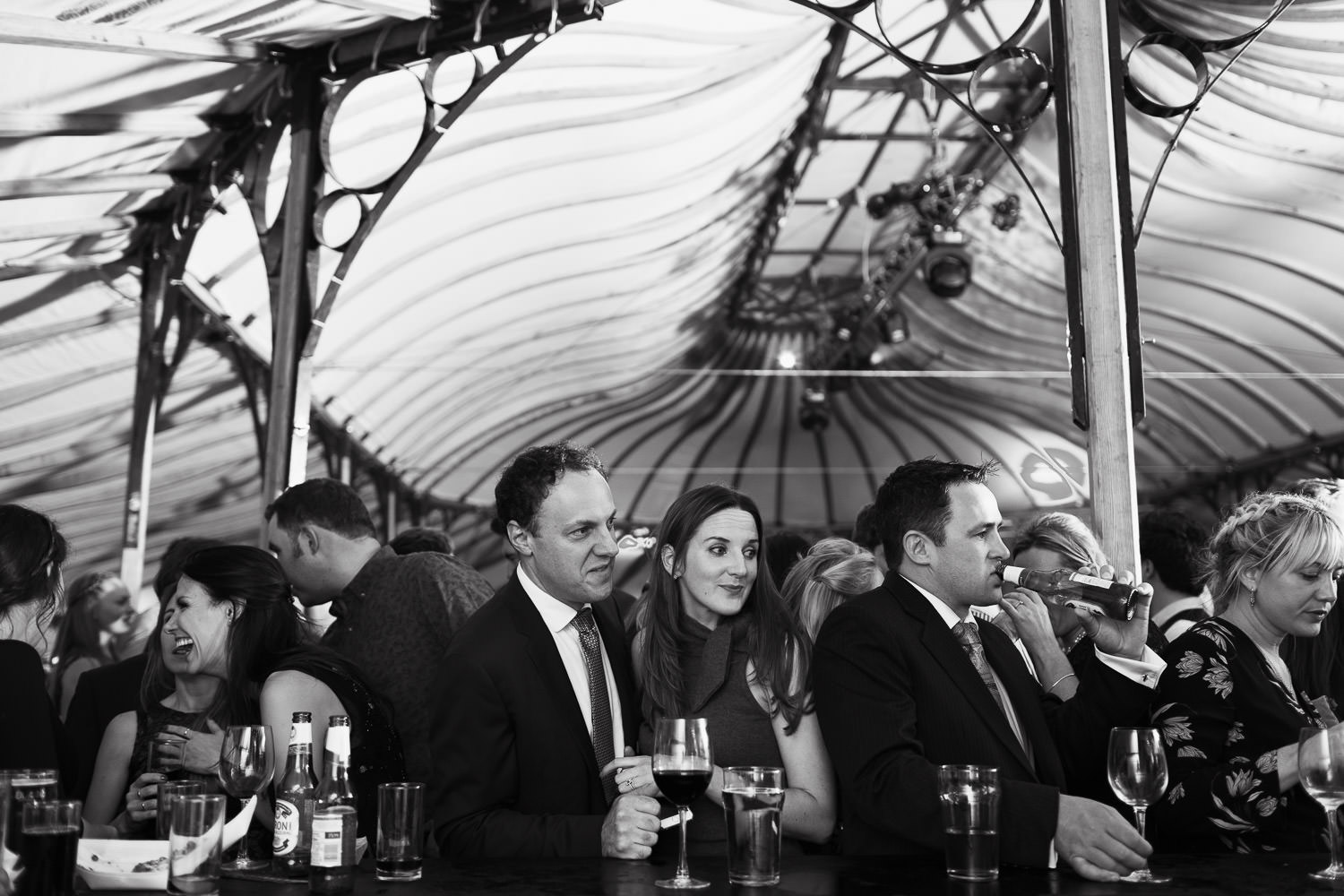 People waiting at the bar in a Bohemia canvas Orangery marquee. Winter wedding.