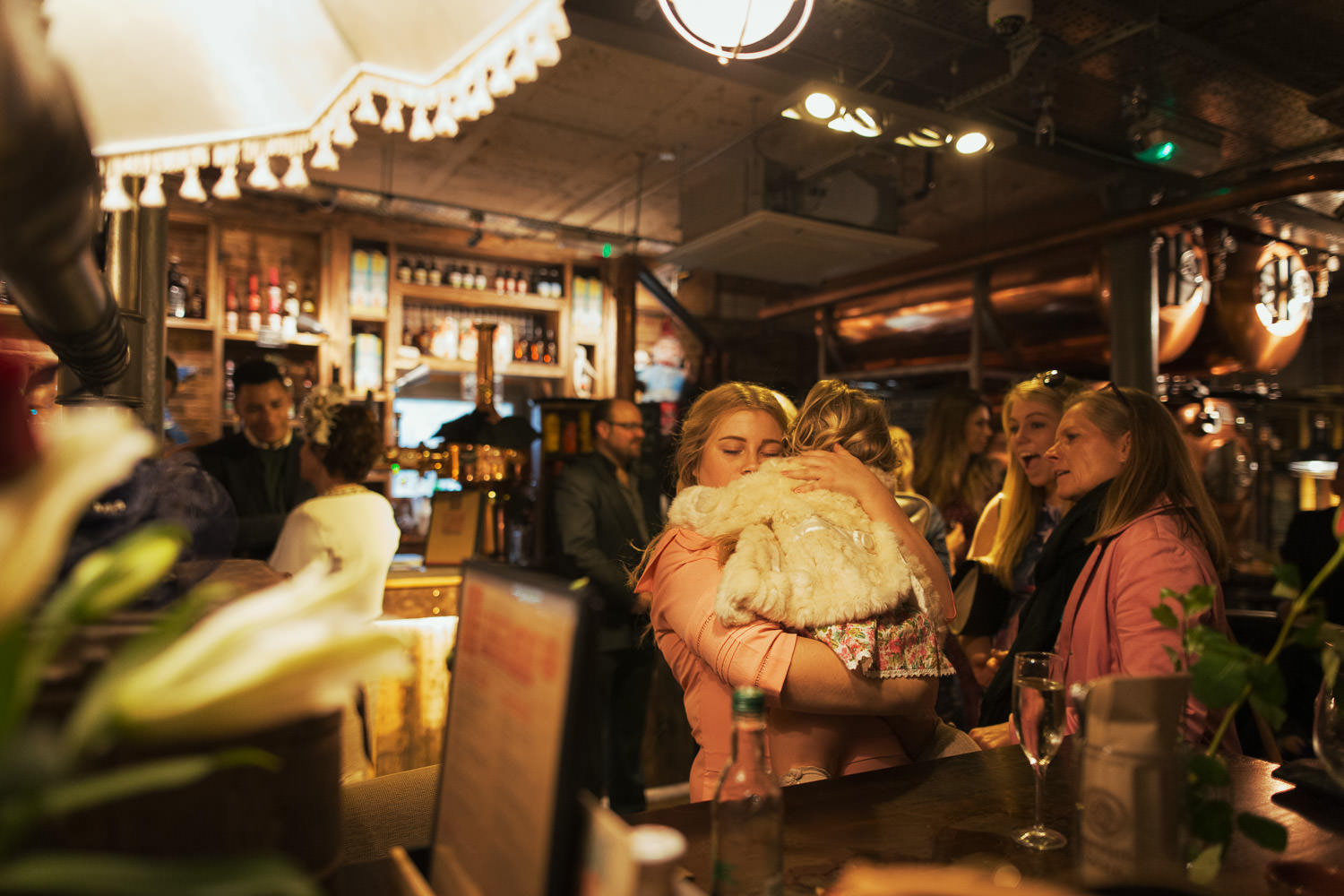 Woman in pink hugging her toddler in a bar at a wedding. Brewhouse and Kitchen bar in Highbury.