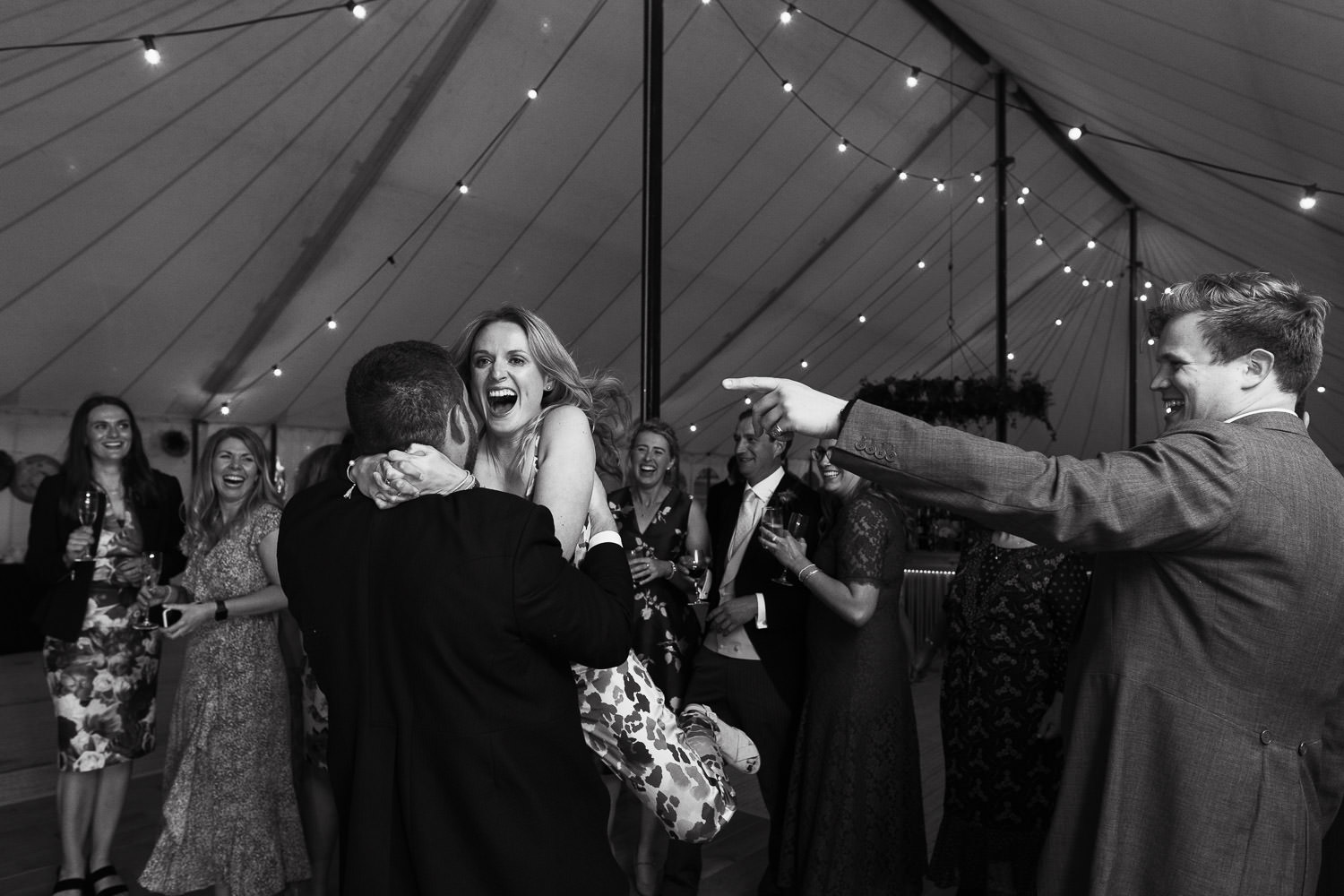 Man lifts up a woman on the dancefloor in a marquee.