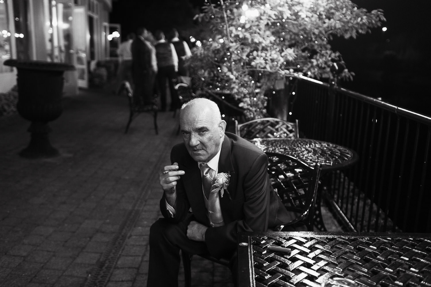 Man on balcony of Kilkenny hotel, smoking a cigarette.