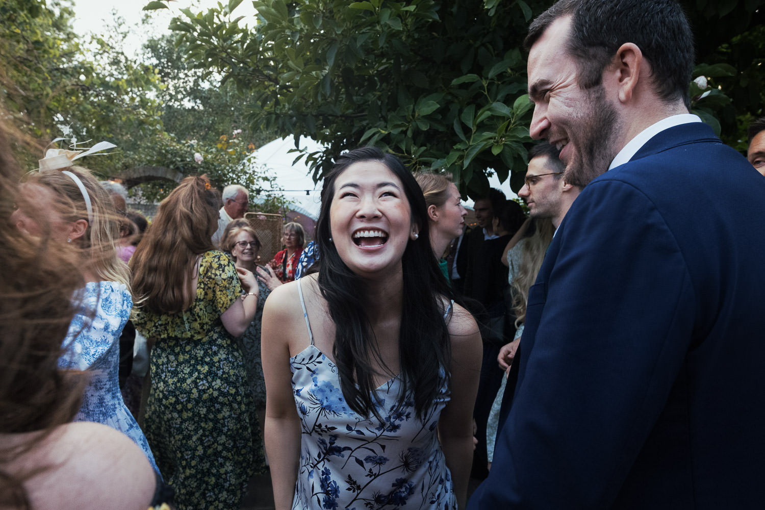 Woman laughing in the garden at a wedding. She's wearing Favorite Daughter The Favorite Dress in blue.