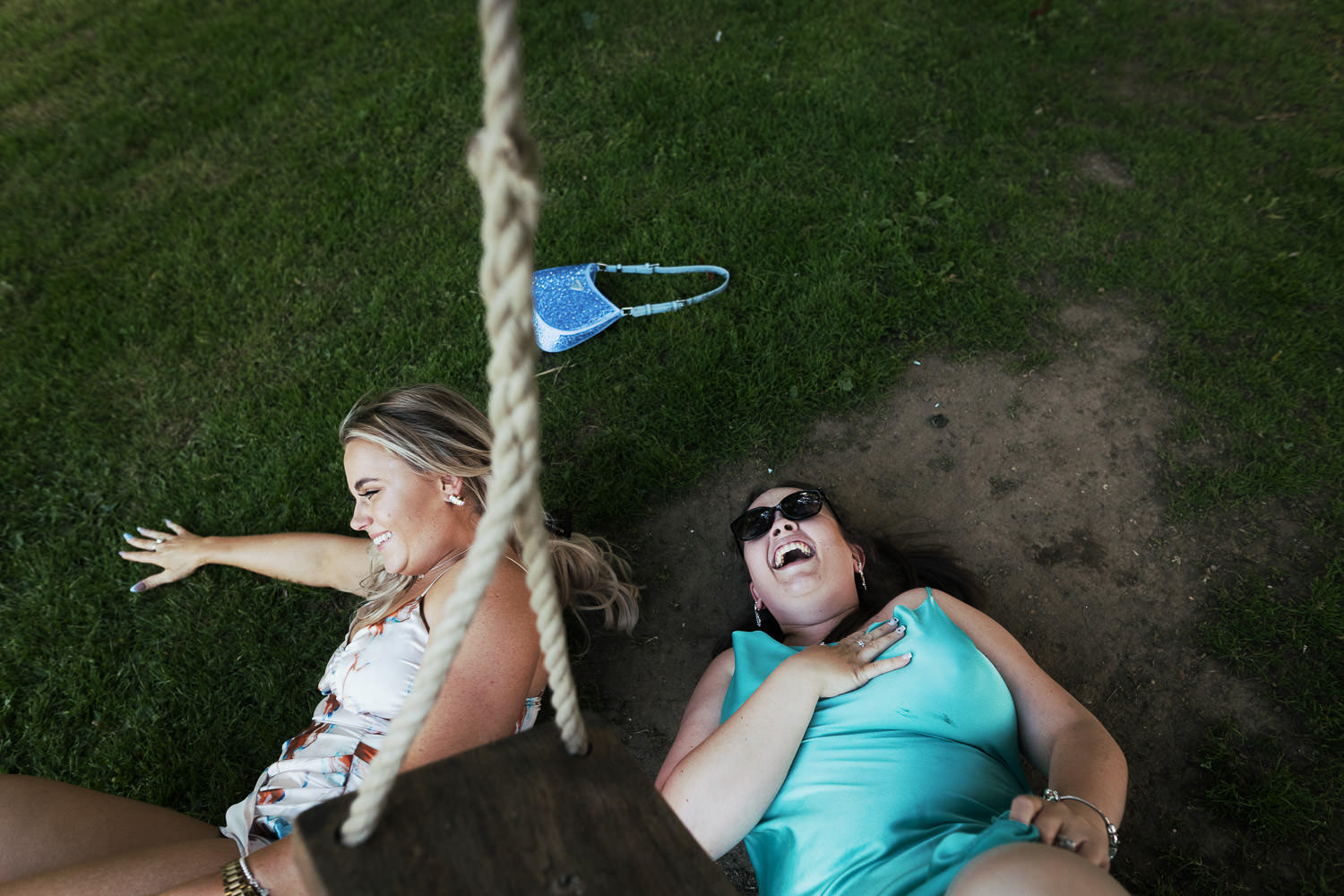 Two wedding guests lying on the grass after falling off the swing. During the evening at Houchins wedding venue in Essex.