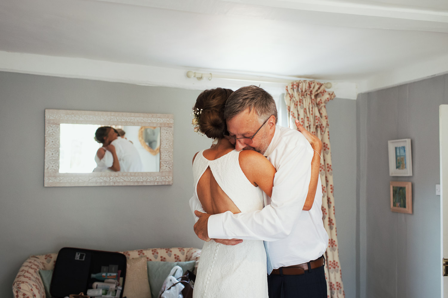 Bride and her father hug before her wedding. They are in a bedroom at Houchins venue in Essex.