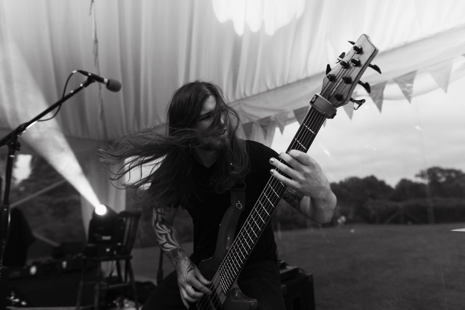 James Beedham, known as Jimmy B, playing bass with Monstaball at a wedding near Shrewsbury in a Muddy Boots Marquee. His long dark hair flowing as he plays.