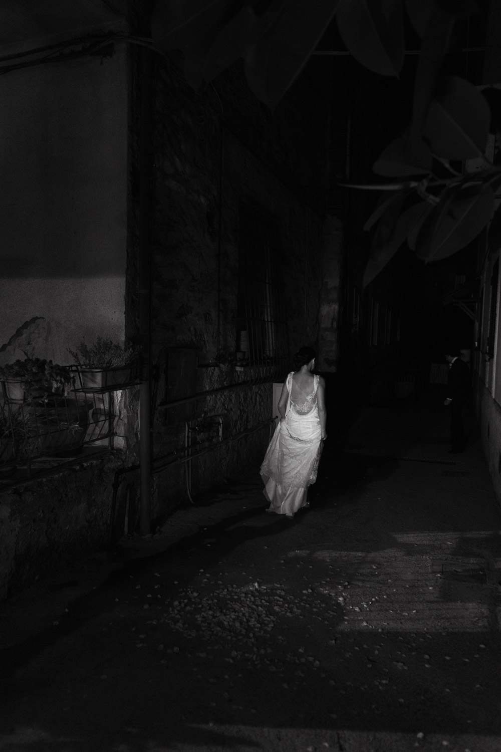 Bride in the red lights of a car walking down alley in the dark at night.