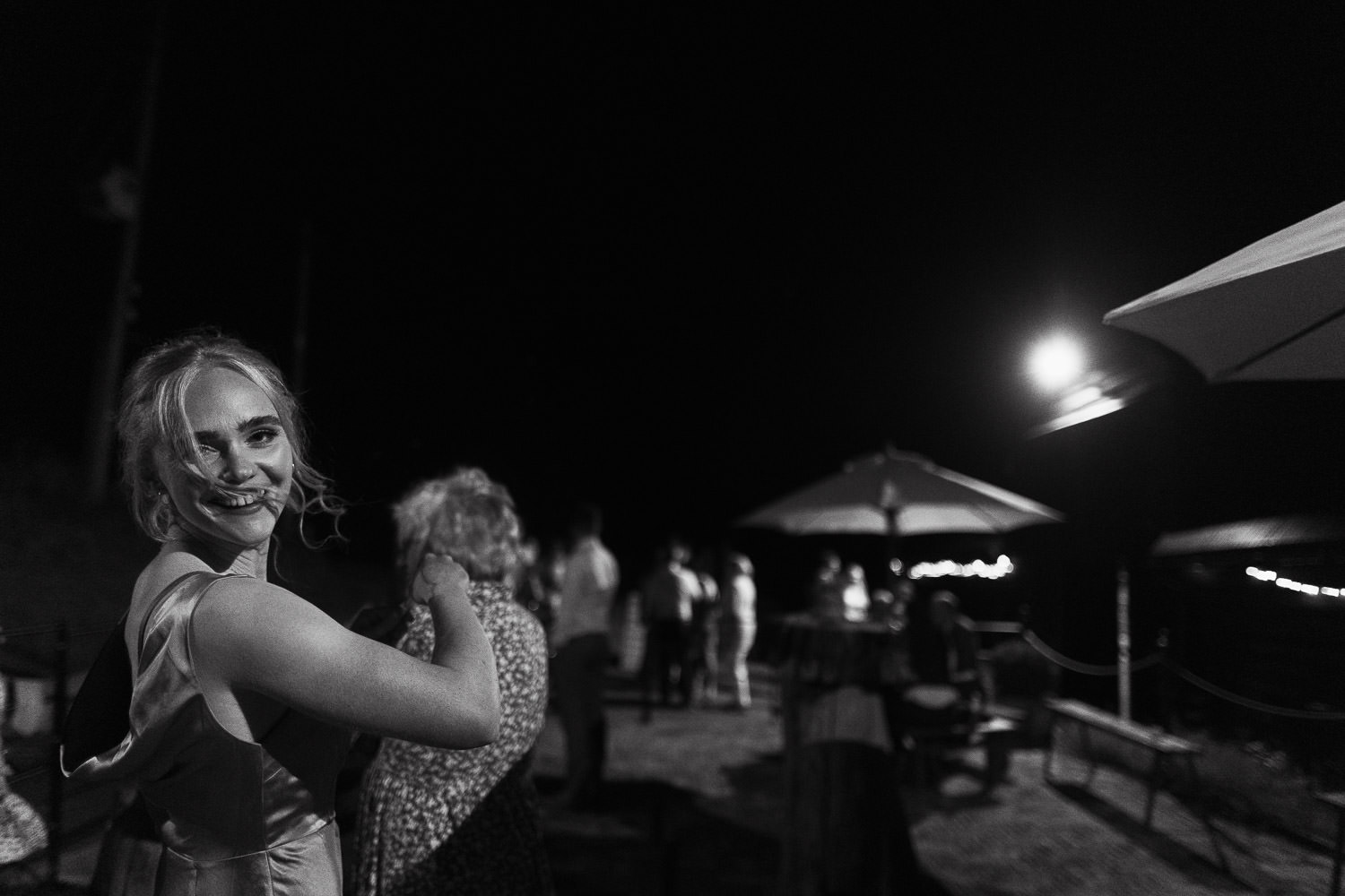 A bridesmaid outside at night looking back at the camera and smiling.