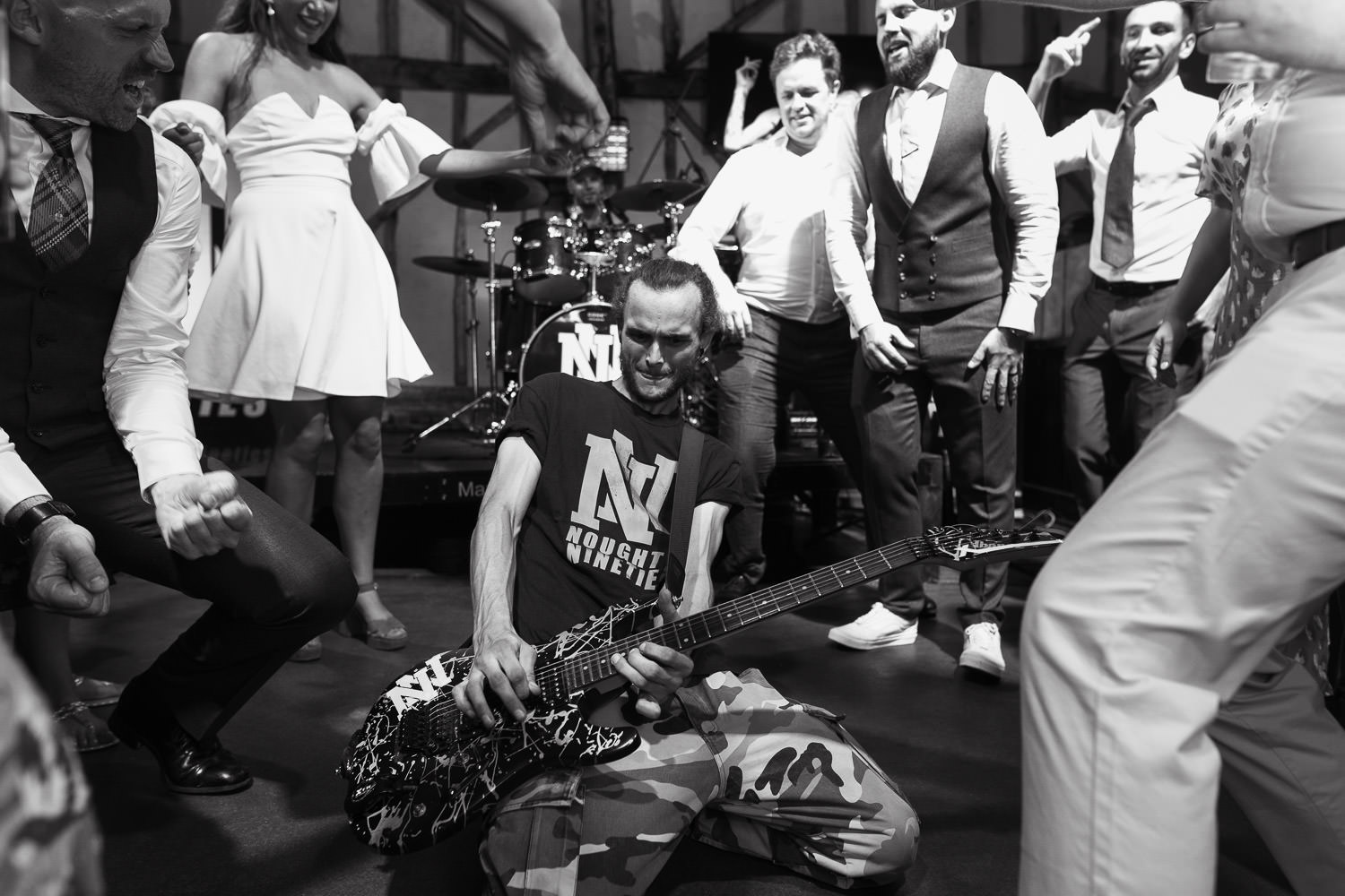 Man on knees playing guitar in band Noughty Nineties performing at Suffolk wedding.