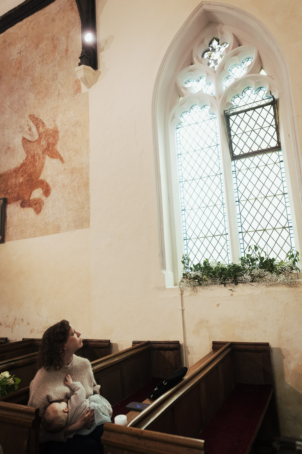 A parent feeding her baby sat on a pew in the Church of St. Mary in Bartlow.