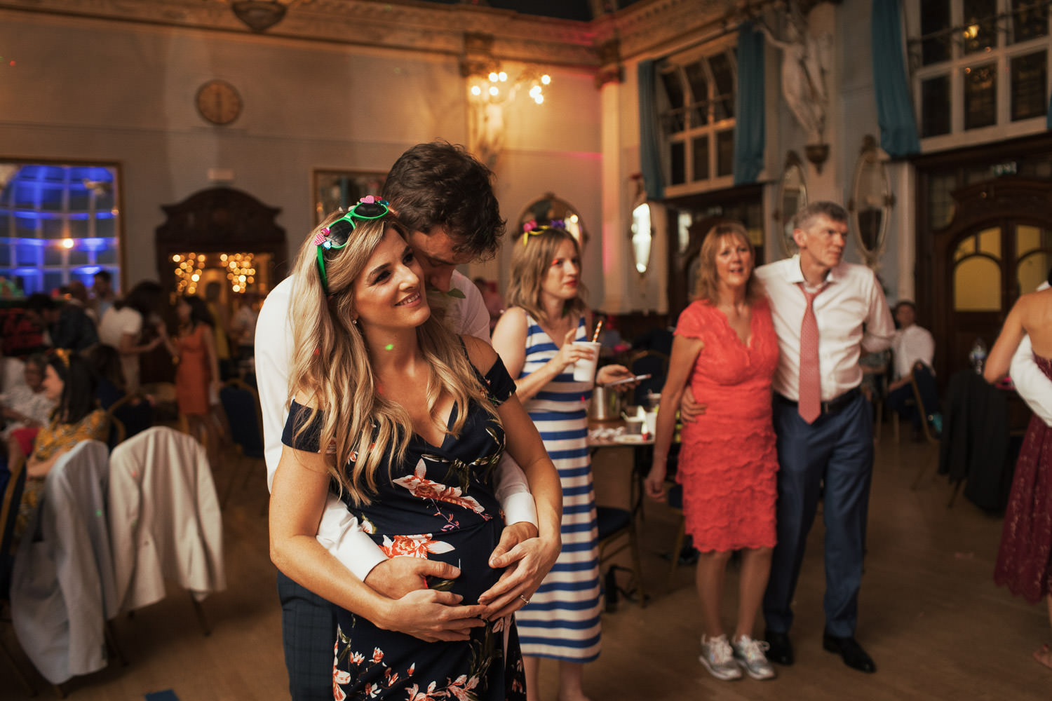 Pregnant woman at a wedding dancing and then kissing her partner at the evening reception.