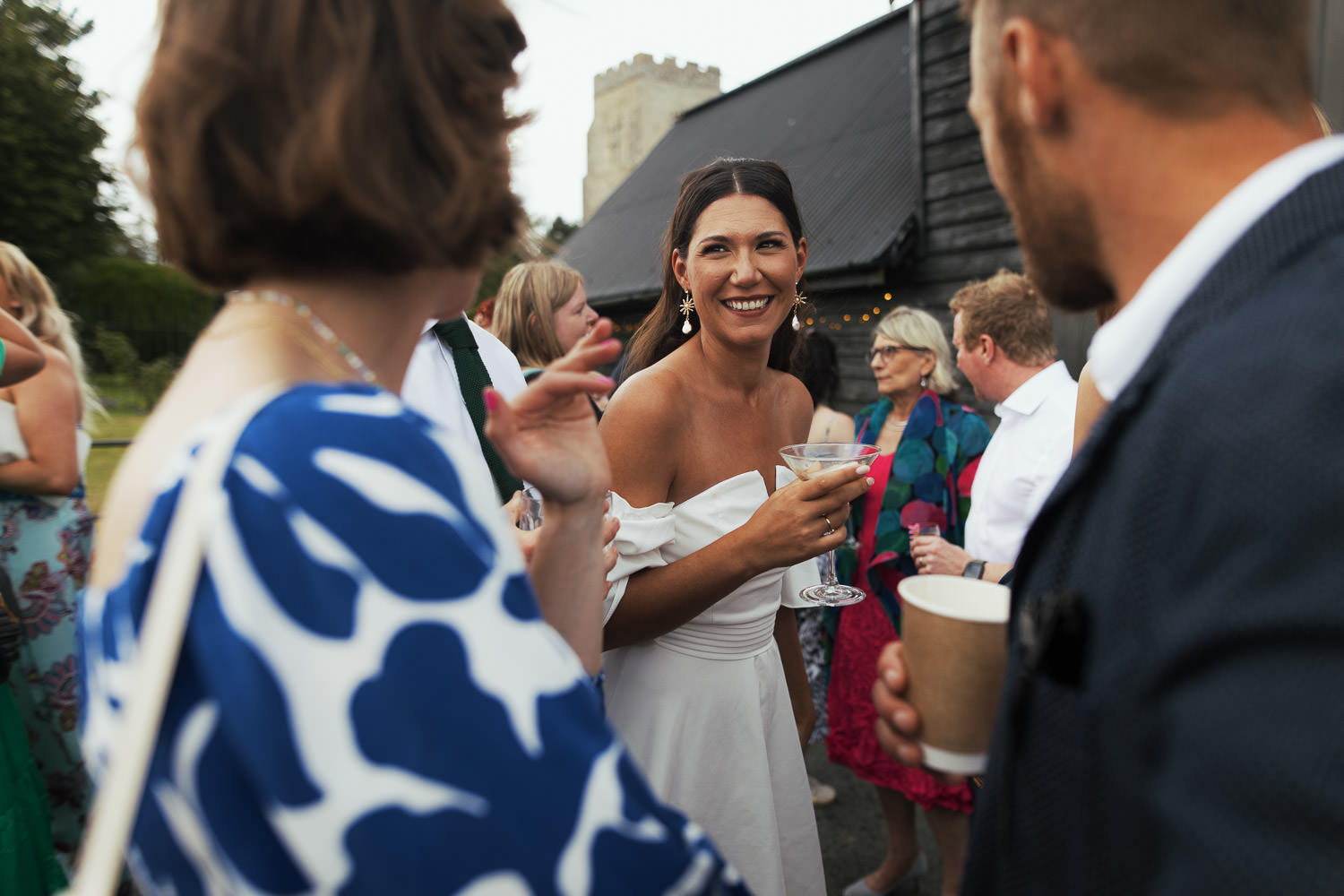 Bride in her reception dress, Trendyol bandeau sleeve mini dress in white, holding espresso martini.