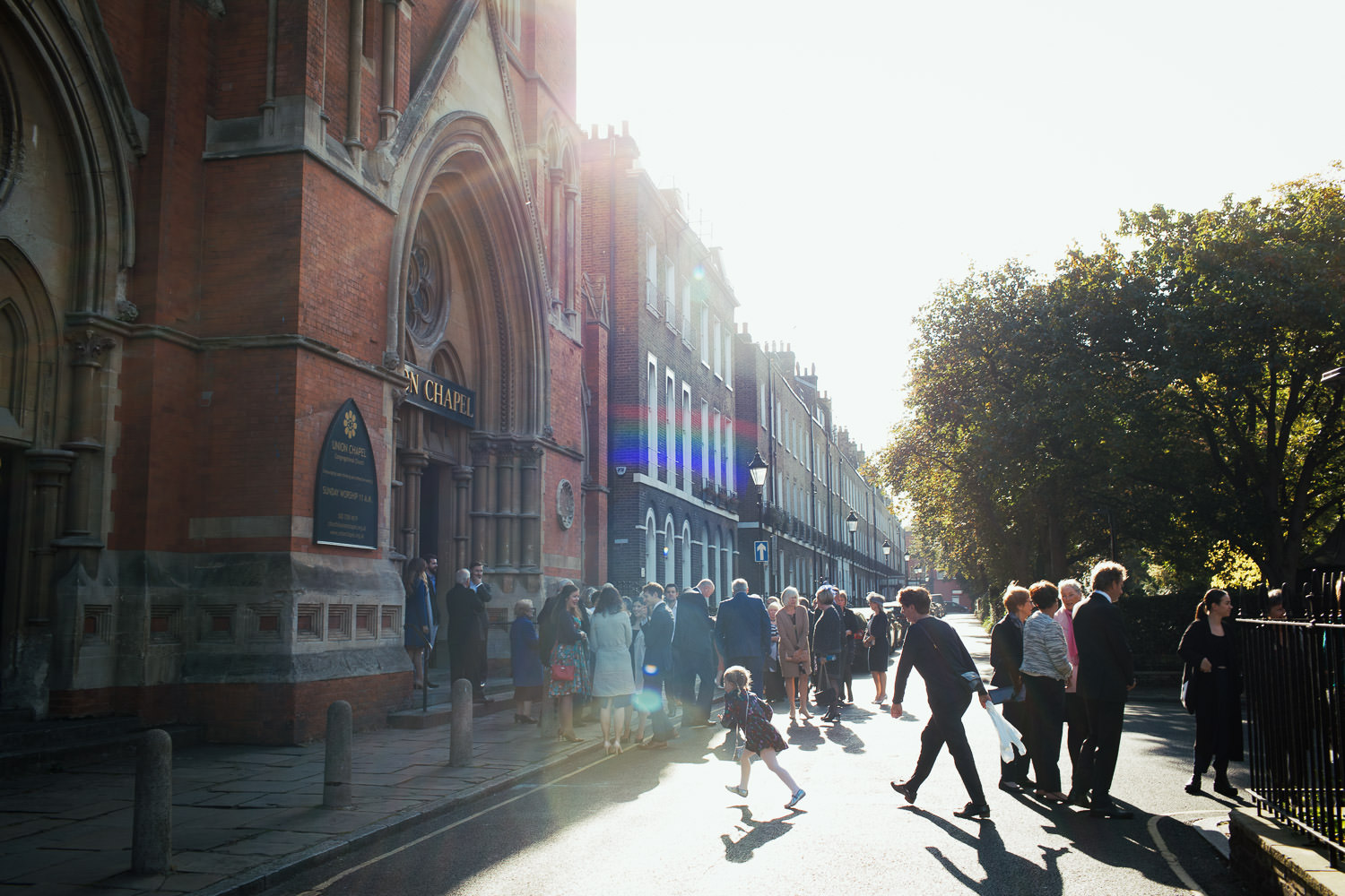 Wedding guests outside the Union Chapel. A girl runs across the road.